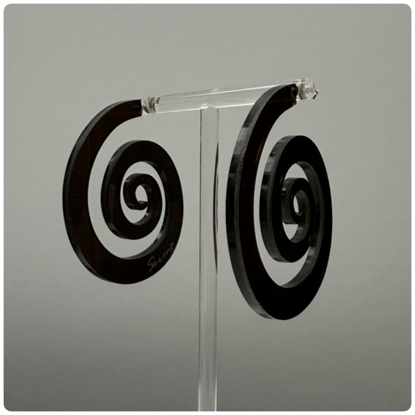 Striking lucite spiral hoop earrings. The spiral represents growth and evolution. The spiral’s outward movement signifies the idea of progress and forward motion. It encourages us to embrace change and continue growing, even when faced with challenges or obstacles. Meticulously handcrafted in the USA, these unique statement pieces feature sterling silver posts and are available in three stunning colors: Smokey grey, opaque white, and neon pink.