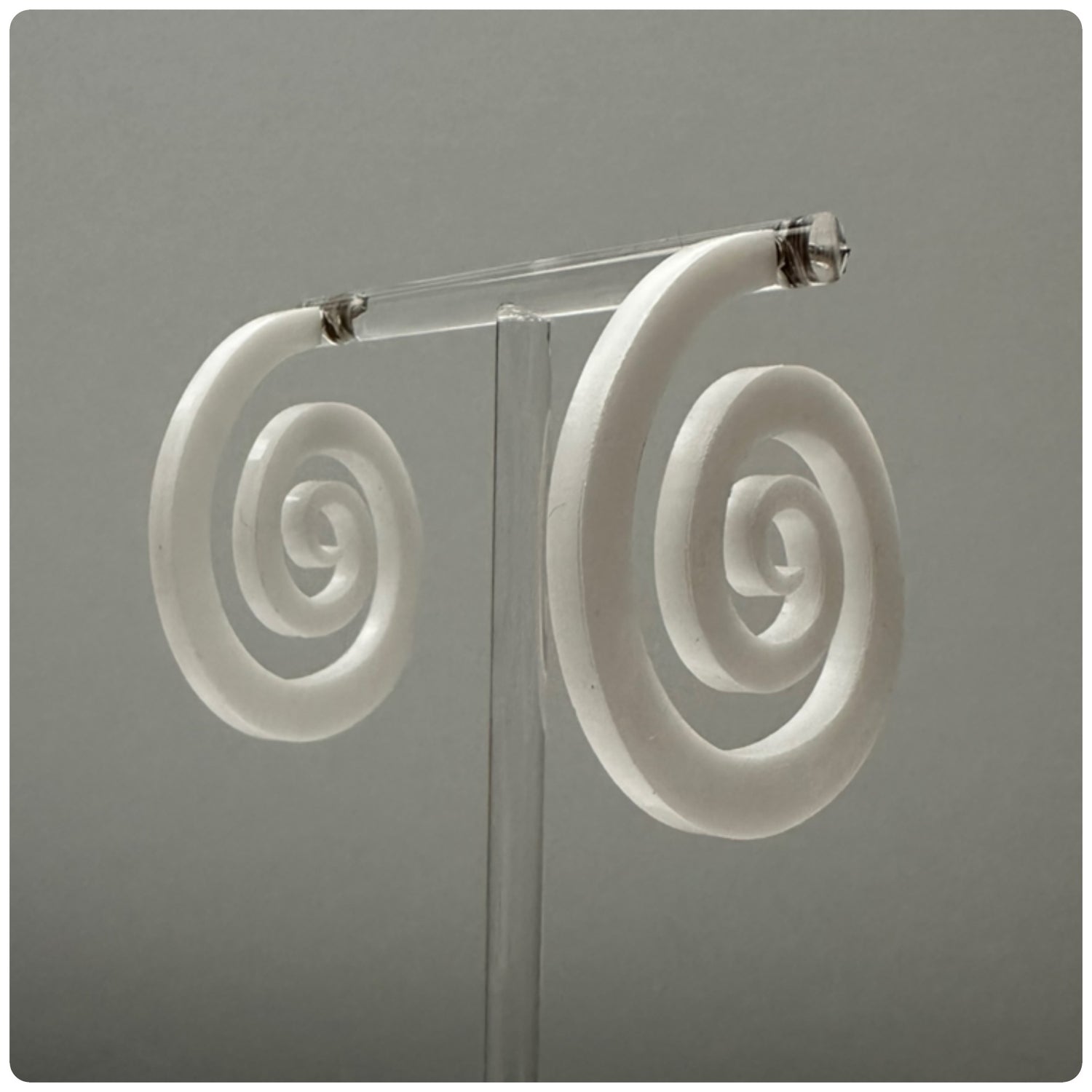 Striking lucite spiral hoop earrings. The spiral represents growth and evolution. The spiral’s outward movement signifies the idea of progress and forward motion. It encourages us to embrace change and continue growing, even when faced with challenges or obstacles. Meticulously handcrafted in the USA, these unique statement pieces feature sterling silver posts and are available in three stunning colors: Smokey grey, opaque white, and neon pink.